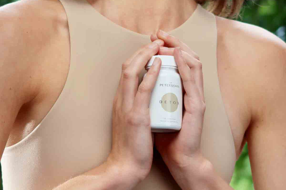 Junge Frau hält das Produkt Detox von Dr. Petersohn vor ihrem Körper.