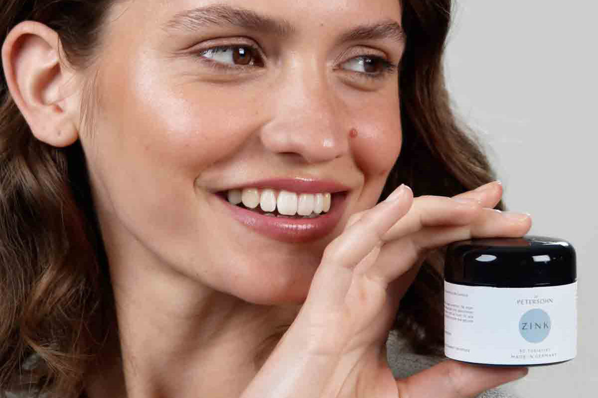 Junge Frau hält das Produkt Zink von Dr. Petersohn in ihrer Hand.