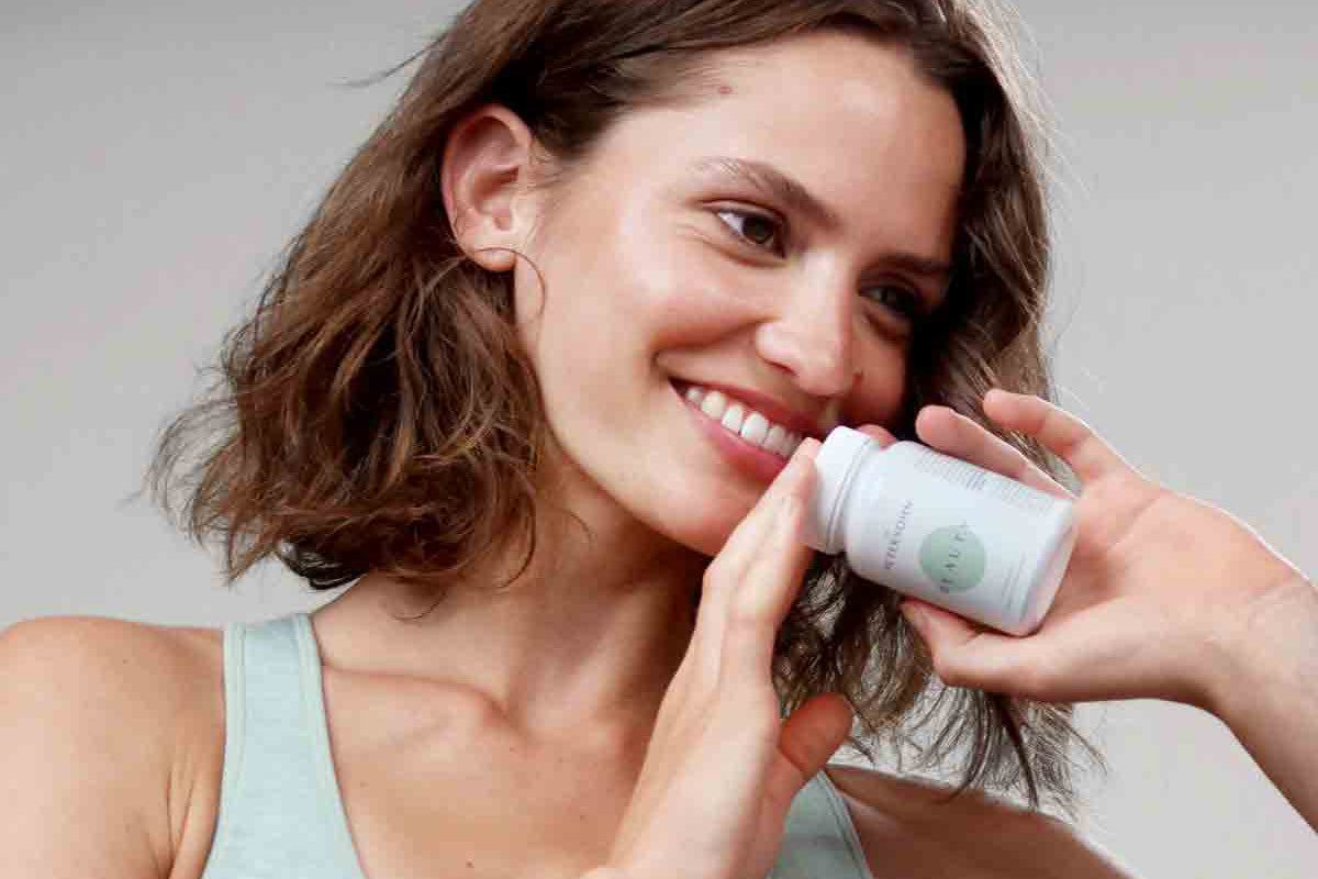 Junge Frau hält das Produkt Beauty von Dr. Petersohn in der Hand.