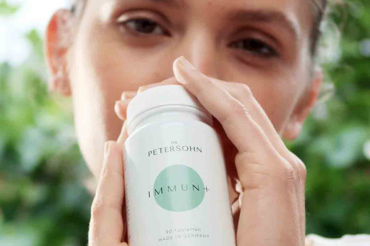 Junge Frau hält das Produkt Immun+ von Dr. Petersohn in ihren Händen.