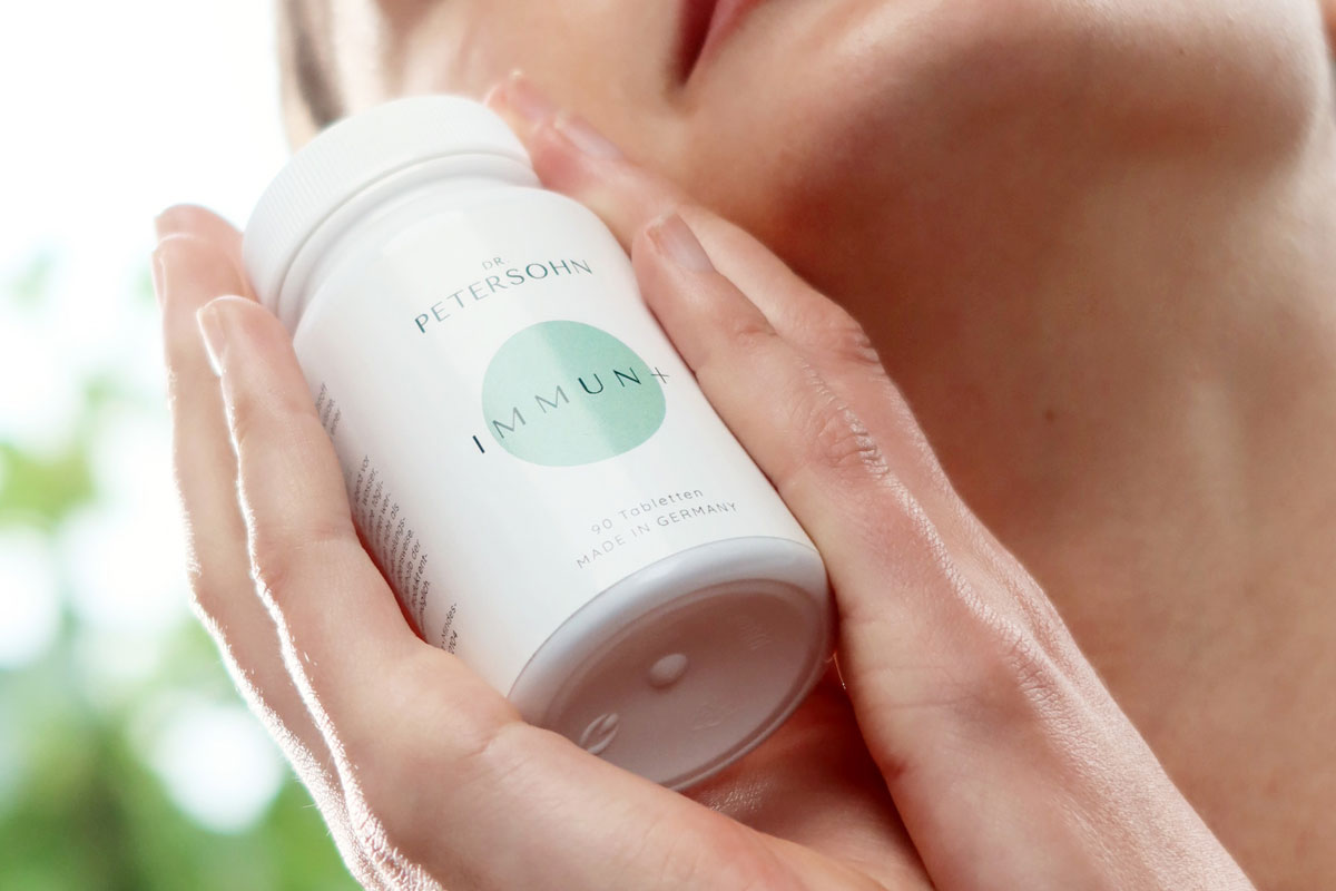 Junge Frau hält das Produkt Immun+ von Dr. Petersohn in ihren Händen.